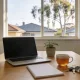 A bright kitchen-dining table with an open laptop, notepad, tea and house keys in soft morning light, ready for first-home savings planning